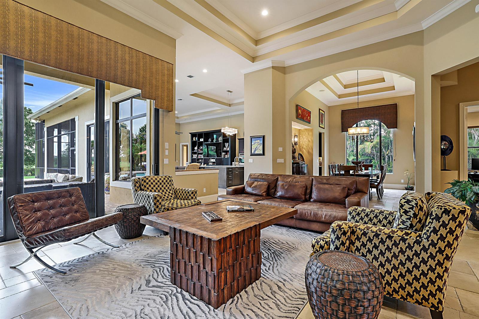 A spacious living room features a leather sofa, patterned armchairs, and a large wooden coffee table — 18337 SE Old Trail Drive W, Jupiter FL 33478, JUPITER, FL