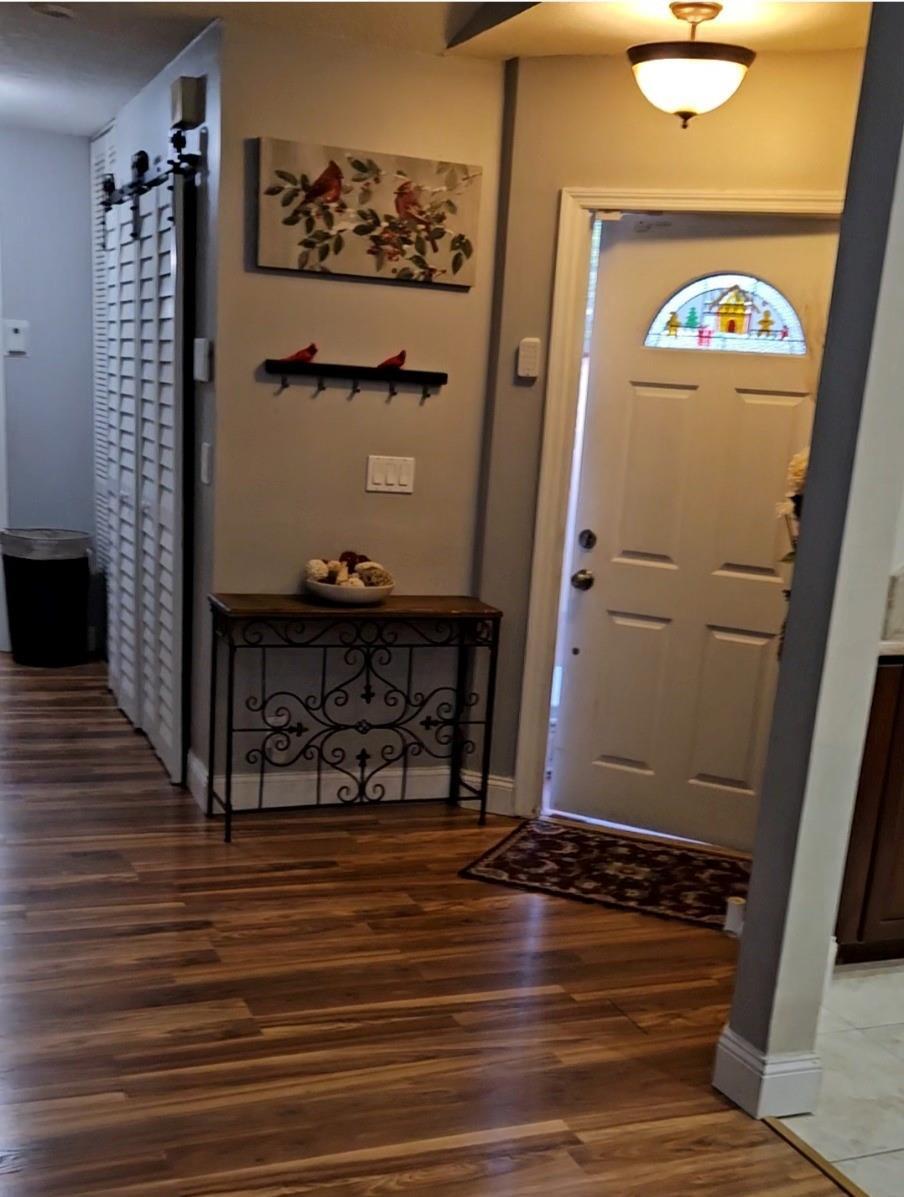 An entryway features a wood-look floor, a console table, wall art, and a white front door — 9215 W Sunrise Boulevard, Plantation FL 33322, PLANTATION, FL