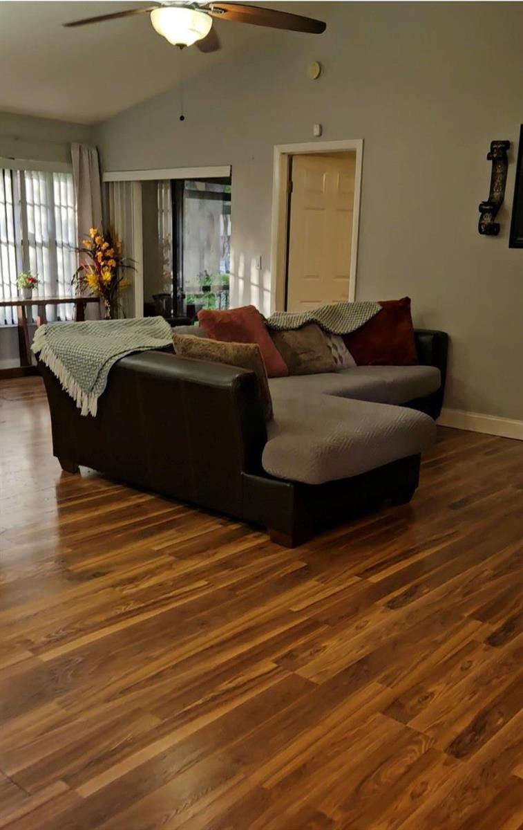 A living room features a dark leather sectional sofa on wood-look flooring under a ceiling fan — 9215 W Sunrise Boulevard, Plantation FL 33322, PLANTATION, FL