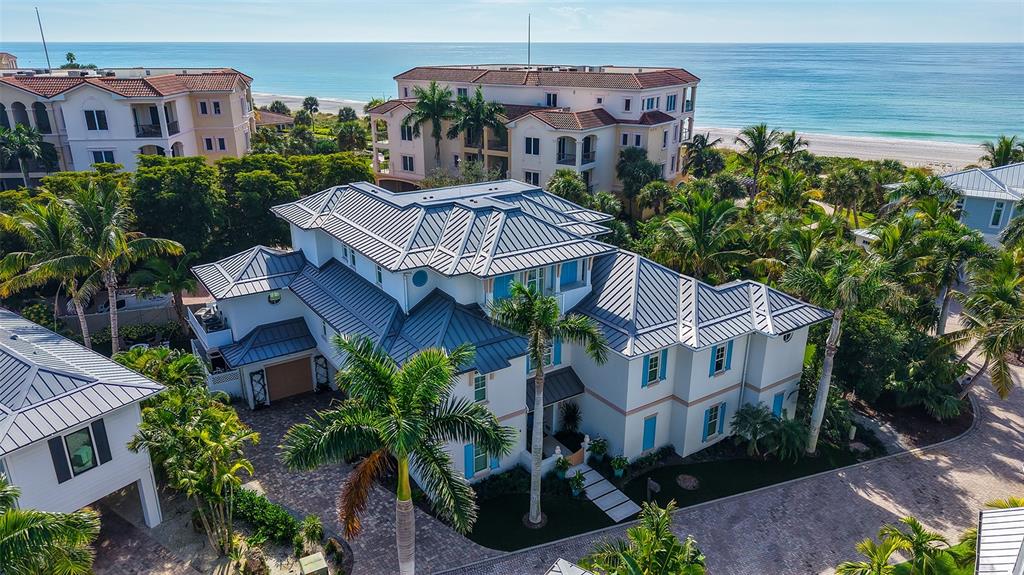 An aerial view of a multi-story coastal home with a metal roof and palm trees — 5005 GULF OF MEXICO DRIVE UNIT 4, LONGBOAT KEY, FL