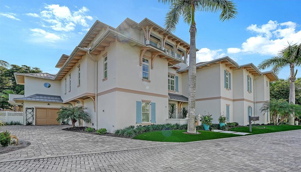 A large, multi-story beige house with a paved driveway and palm trees under a blue sky — 5005 GULF OF MEXICO DRIVE UNIT 4, LONGBOAT KEY, FL