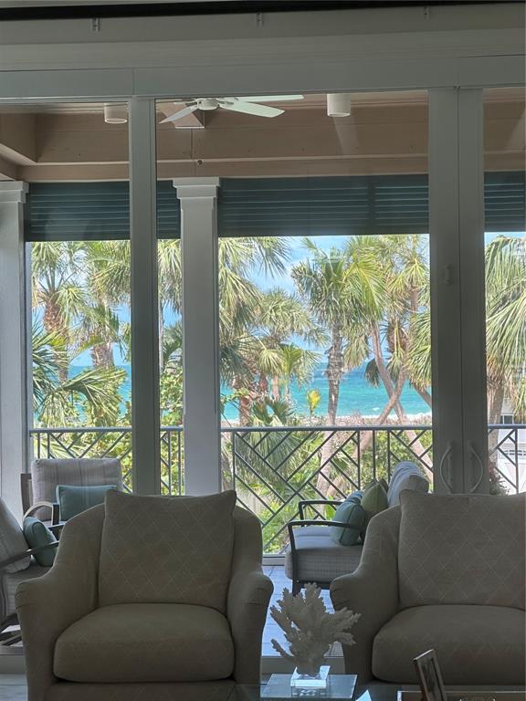 A living room with two armchairs overlooks a balcony with palm trees and the ocean — 5005 GULF OF MEXICO DRIVE UNIT 4, LONGBOAT KEY, FL