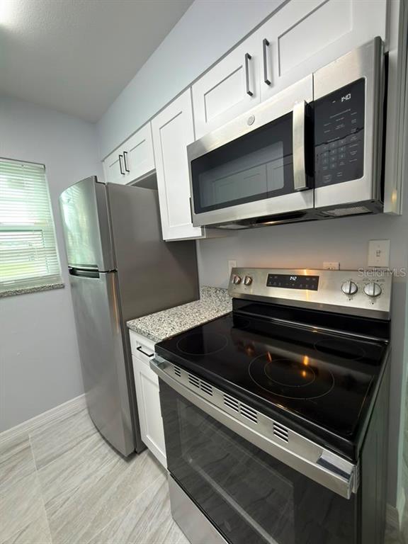 A kitchen features stainless steel appliances, white cabinets, and granite countertops — 843 SKY LAKE CIRCLE UNIT B, ORLANDO, FL