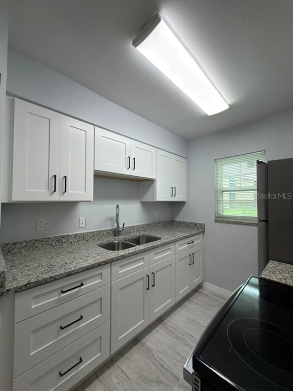 A kitchen features white cabinets, granite countertops, a double sink, and a stainless steel stove — 843 SKY LAKE CIRCLE UNIT B, ORLANDO, FL