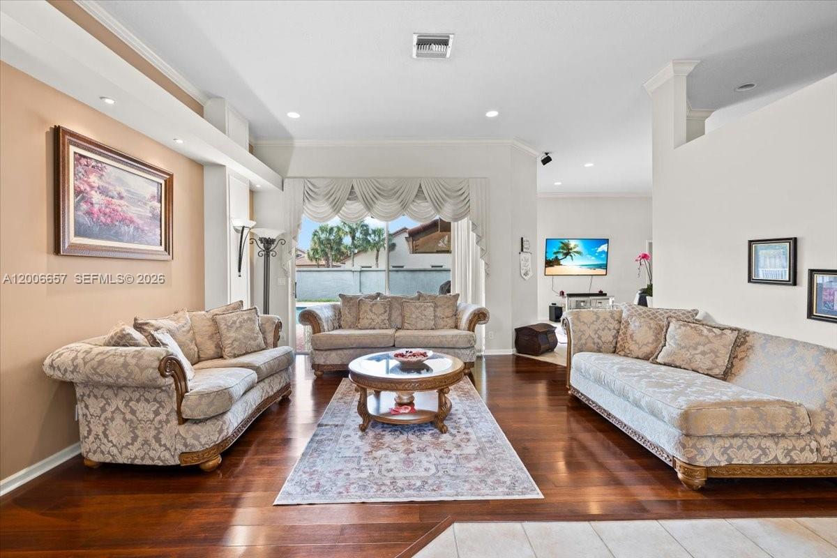 A living room features hardwood floors, three sofas, a coffee table, and large sliding doors — 10912 NW 2nd St, Plantation FL 33324, PLANTATION, FL