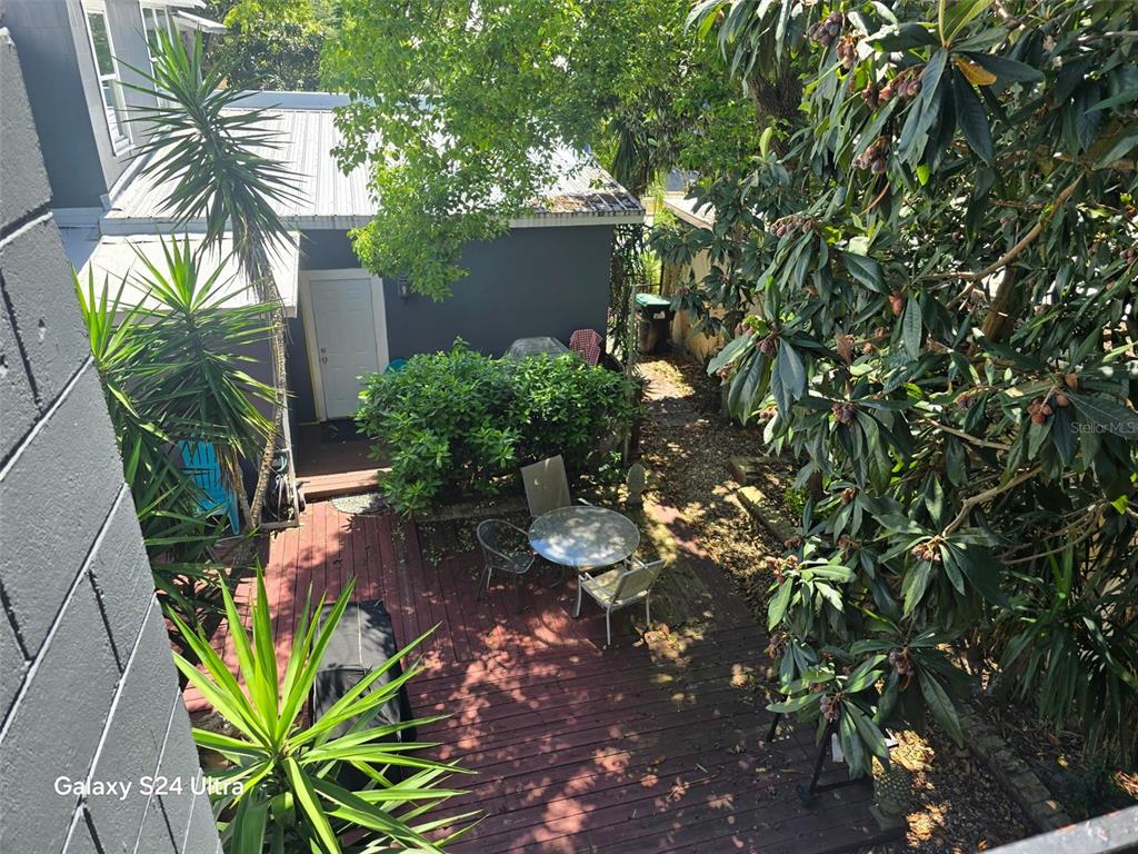 An elevated view of a wooden deck with a small table, chairs, and surrounding landscaping — 7306 EARLWOOD AVENUE, MOUNT DORA, FL