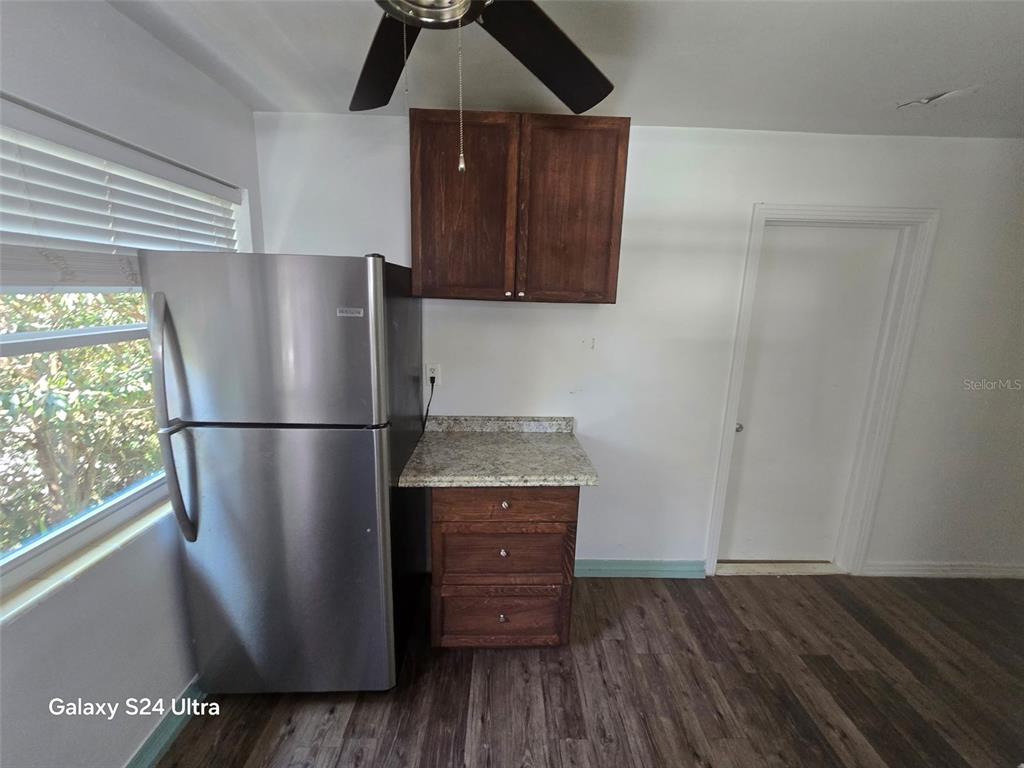 A kitchen area features a stainless steel refrigerator, dark wood cabinets, and granite countertops — 7306 EARLWOOD AVENUE, MOUNT DORA, FL