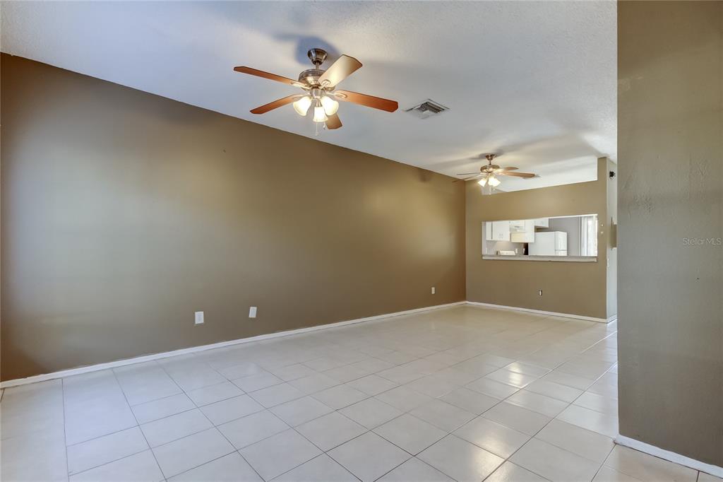 An empty living room features tan walls, white tile flooring, and two ceiling fans — 6318 BAYSIDE KEY DRIVE, TAMPA, FL