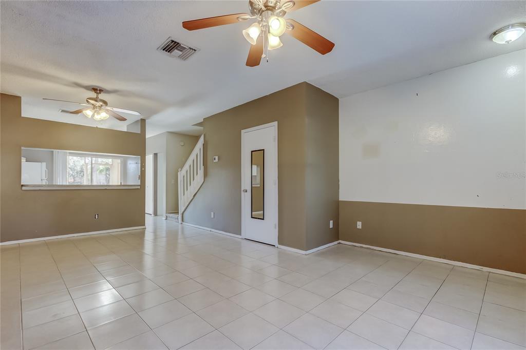 A living room with tile flooring, two ceiling fans, and a staircase — 6318 BAYSIDE KEY DRIVE, TAMPA, FL