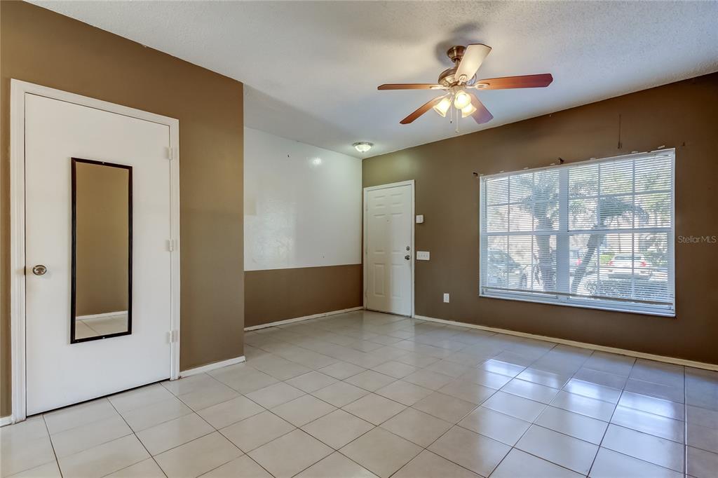 A room with tan walls, white tile flooring, a ceiling fan, and two white doors — 6318 BAYSIDE KEY DRIVE, TAMPA, FL