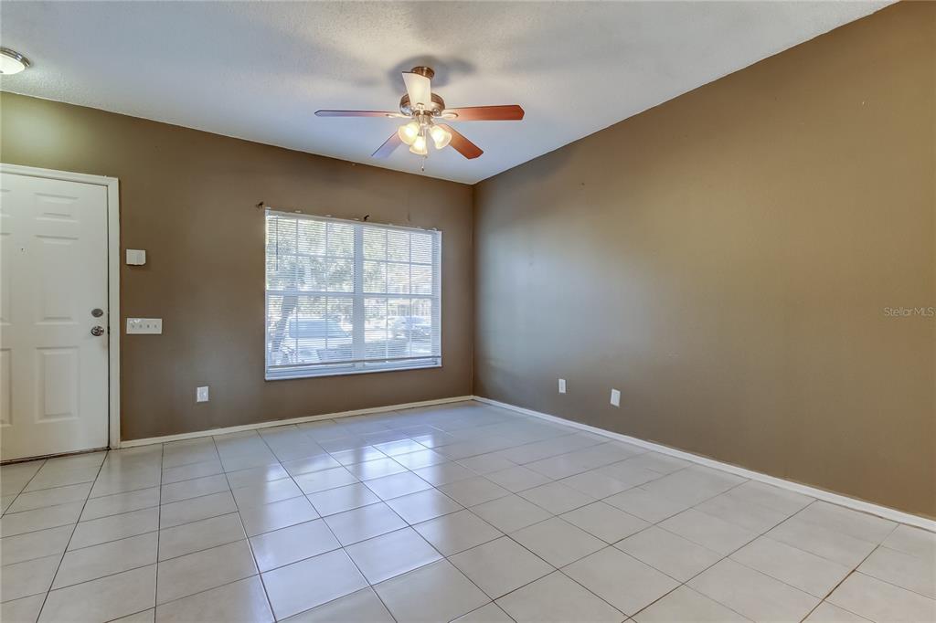 An empty room features tan walls, white tiled flooring, a ceiling fan, and a window — 6318 BAYSIDE KEY DRIVE, TAMPA, FL