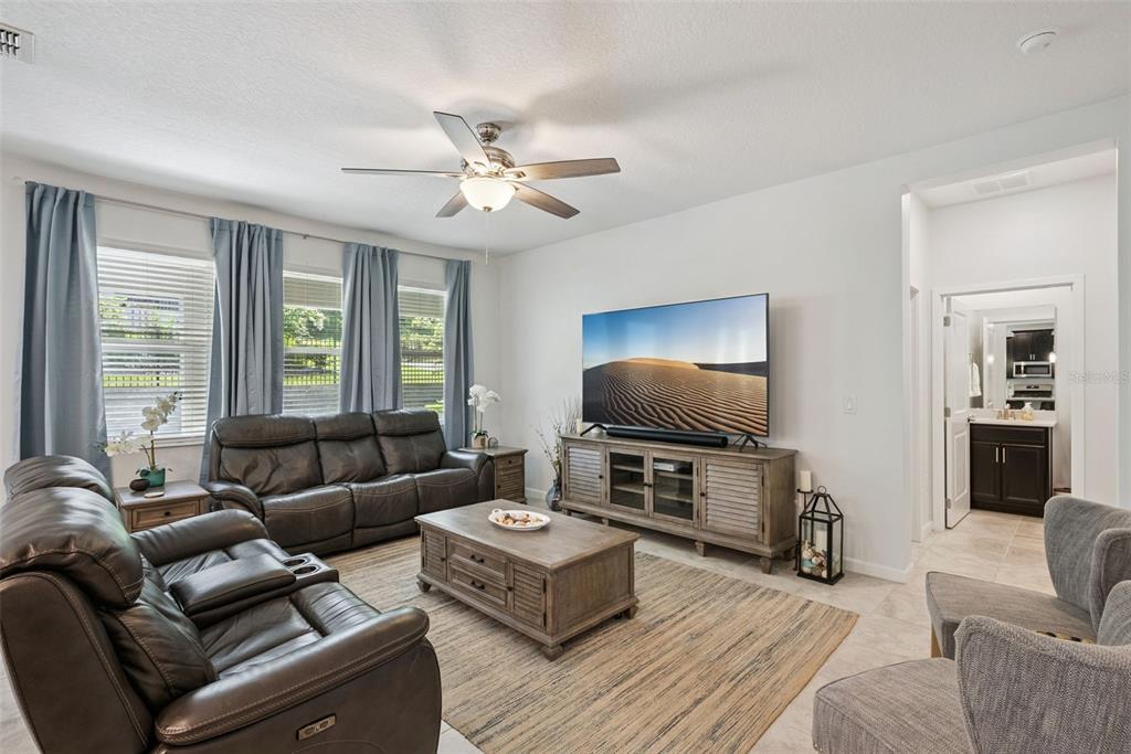 A living room features dark leather sofas, a wooden coffee table, and a wall-mounted television — 1235 DORA PARC LANE, MOUNT DORA, FL