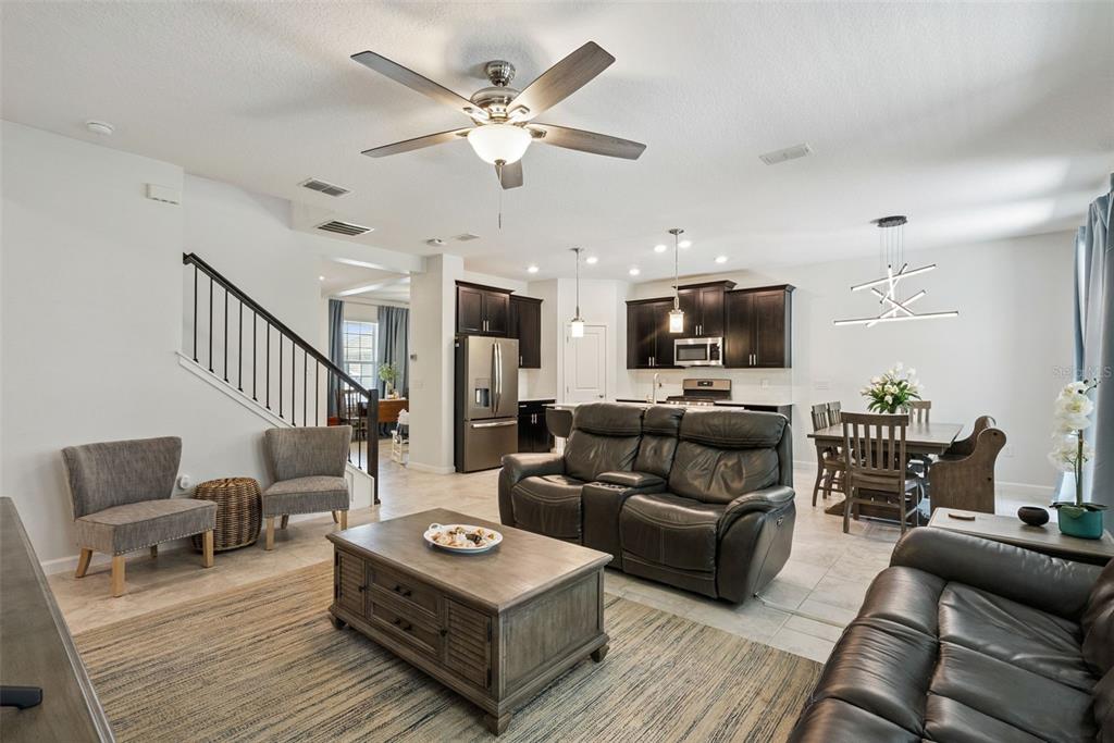 An open-concept living and dining area features dark cabinetry, tile flooring, and a ceiling fan — 1235 DORA PARC LANE, MOUNT DORA, FL