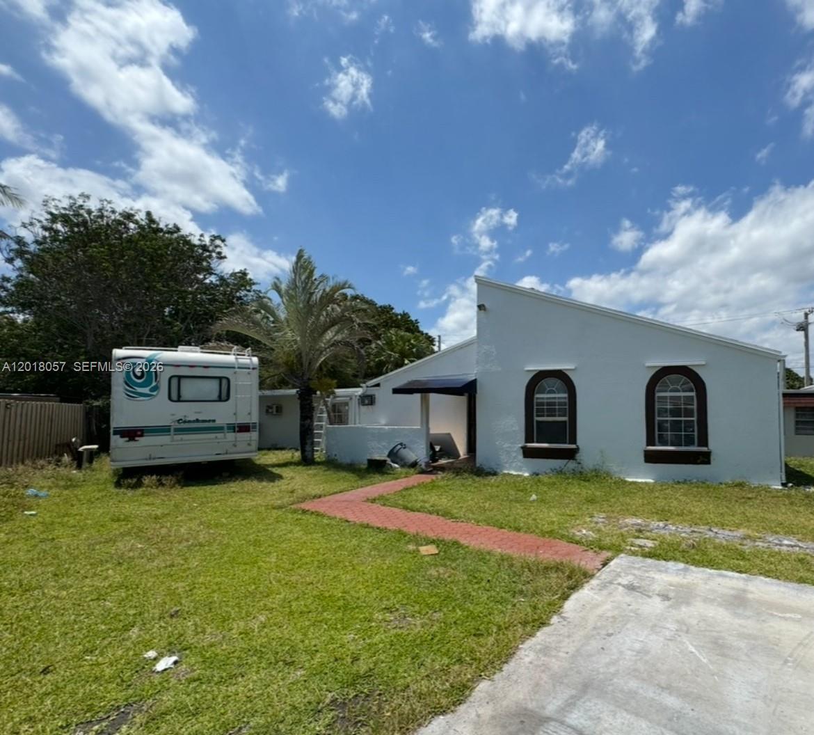 A white single-story house with arched windows sits next to a parked recreational vehicle — 19422 SW 119th Ct, Miami FL 33177, MIAMI, FL