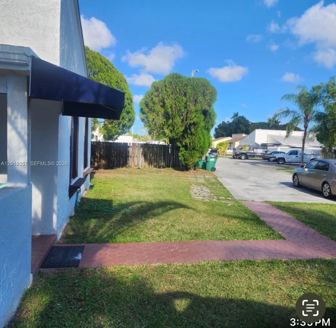 A side view of a house exterior with a lawn, walkway, and adjacent parking area — 19422 SW 119th Ct, Miami FL 33177, MIAMI, FL