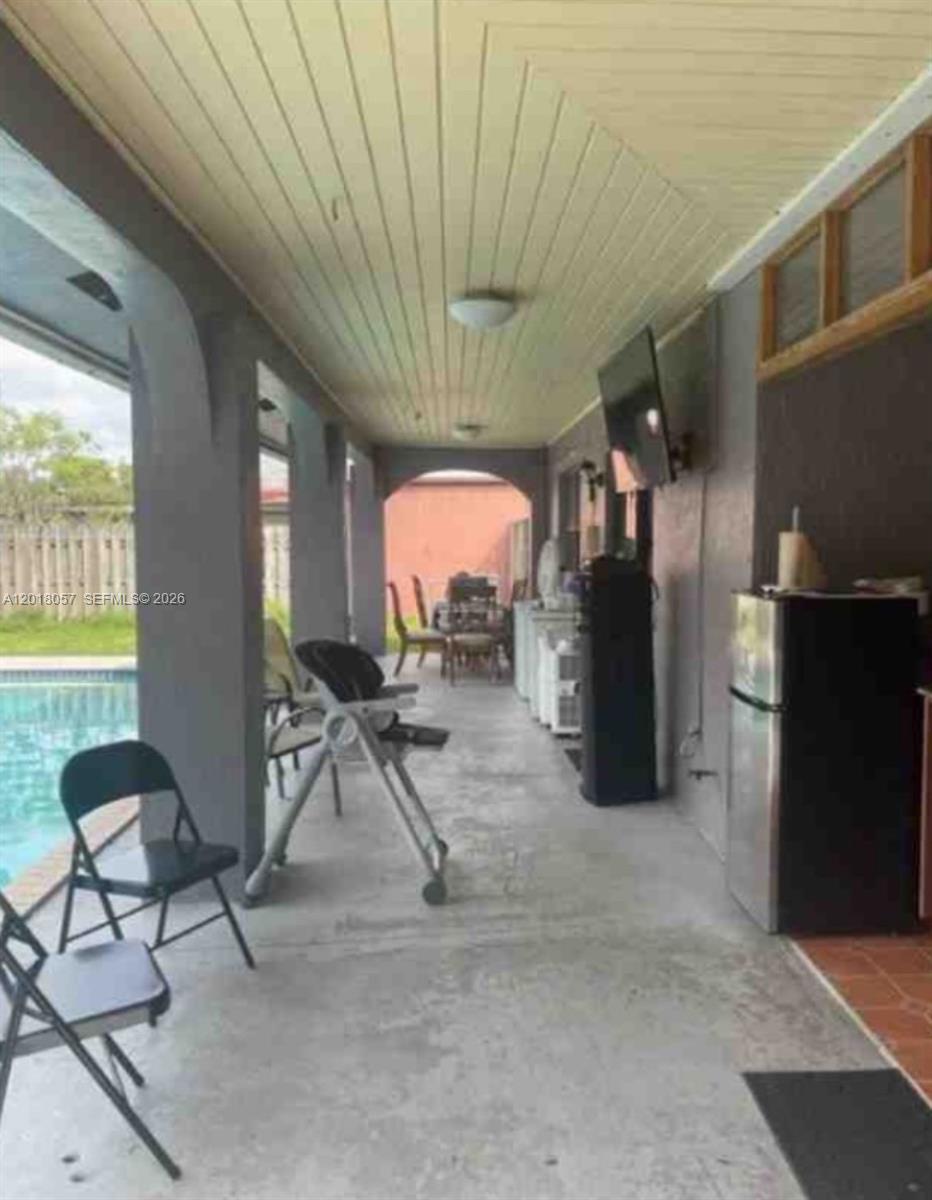 A covered outdoor patio features a concrete floor, a ceiling fan, and a swimming pool — 19422 SW 119th Ct, Miami FL 33177, MIAMI, FL