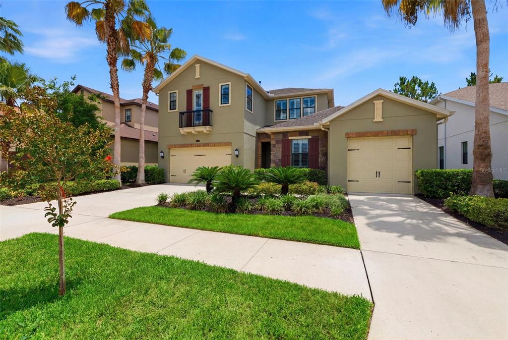 A two-story house with a tan stucco exterior, two garages, and a small balcony — 14231 AVON FARMS DRIVE, TAMPA, FL