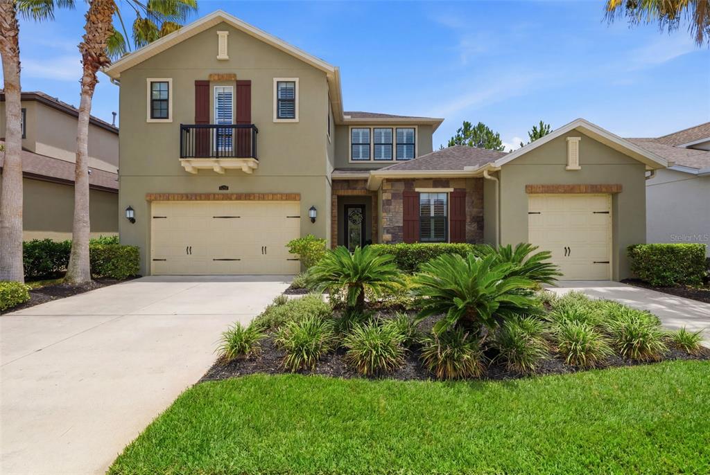 A two-story suburban house with a three-car garage, a balcony, and a landscaped front yard — 14231 AVON FARMS DRIVE, TAMPA, FL
