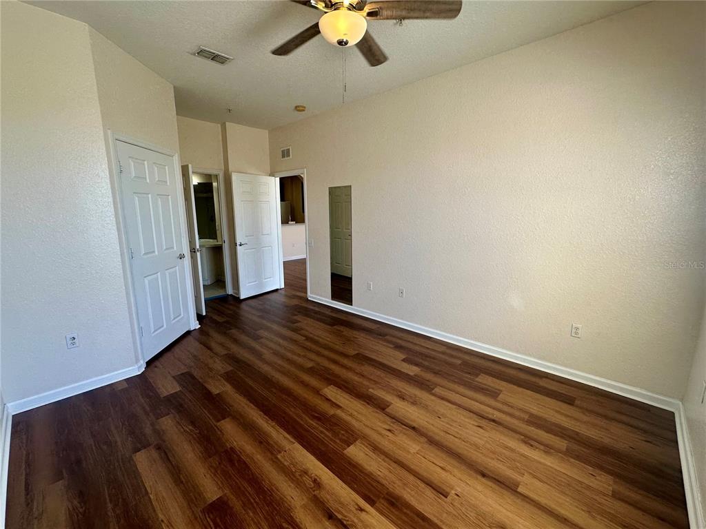An empty bedroom features wood-look flooring, a ceiling fan, and two white interior doors — 6402 CAVA ALTA DRIVE UNIT 410, ORLANDO, FL