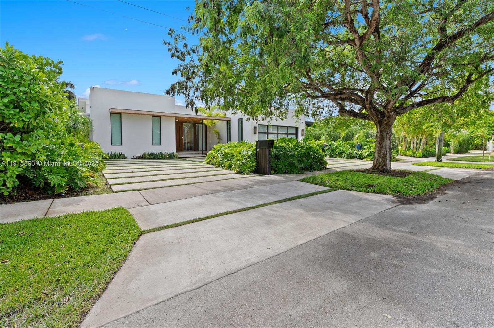 A modern white house features a concrete driveway with grass strips and a large tree — 1792 Cleveland Rd, Miami Beach FL 33141, MIAMI BEACH, FL