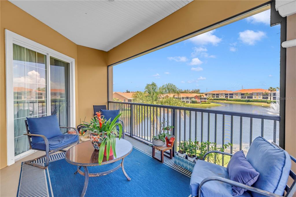 A screened-in balcony features blue patio furniture, a glass-top table, and a view of water — 10 FRANKLIN COURT S UNIT 63D, ST PETERSBURG, FL