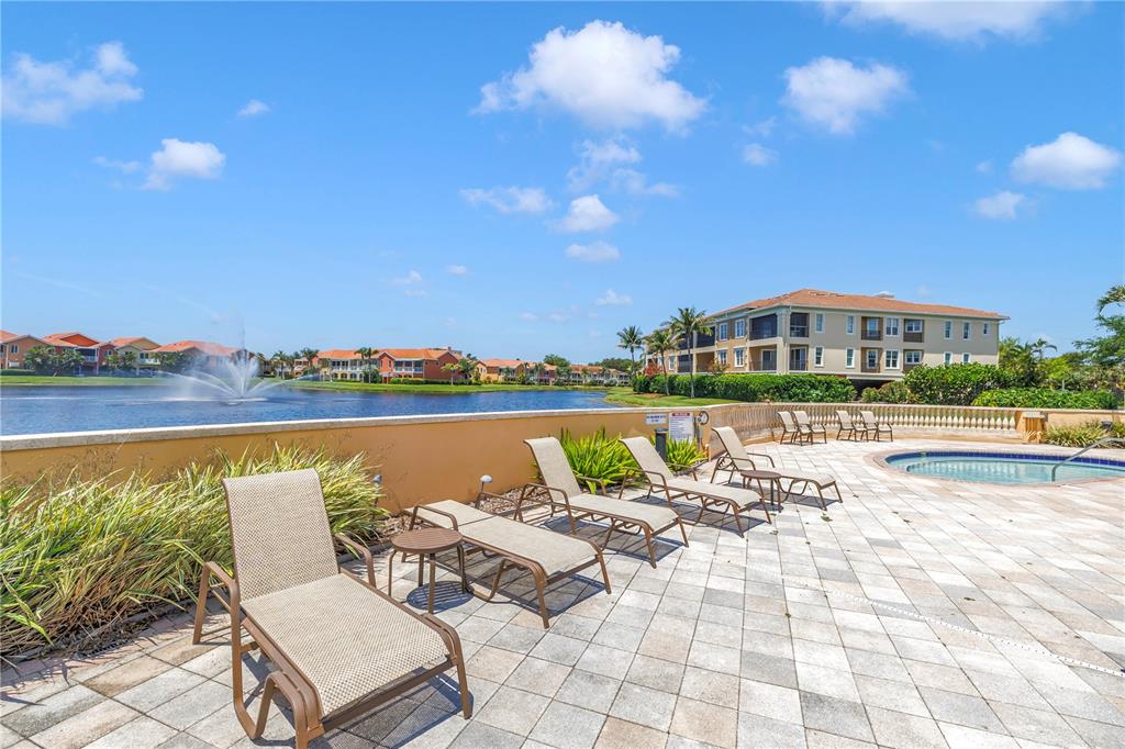 A pool deck with lounge chairs overlooks a lake with a fountain and apartment buildings — 10 FRANKLIN COURT S UNIT 63D, ST PETERSBURG, FL