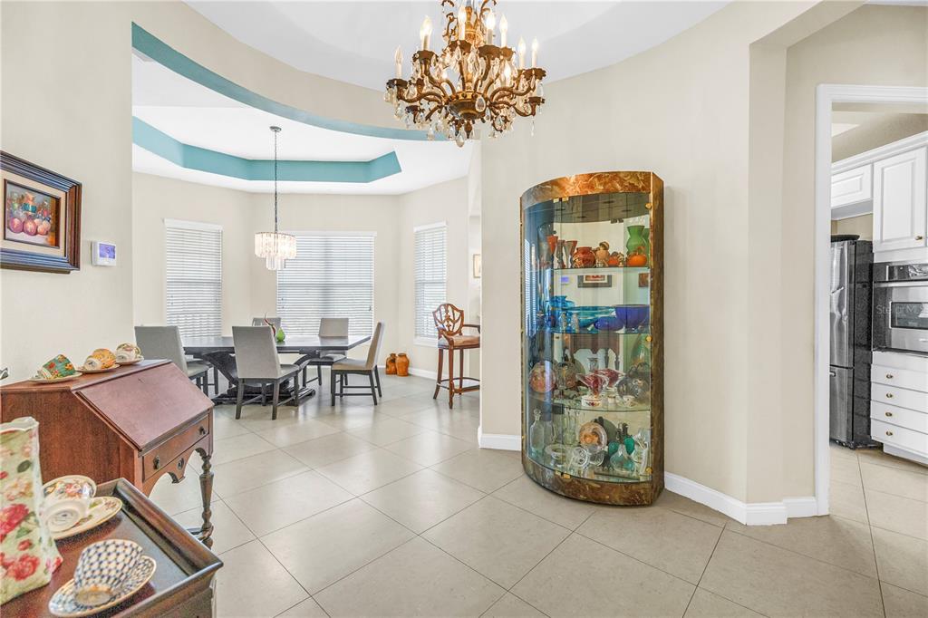 A dining area features a chandelier, a curved glass display cabinet, and tile flooring — 10 FRANKLIN COURT S UNIT 63D, ST PETERSBURG, FL