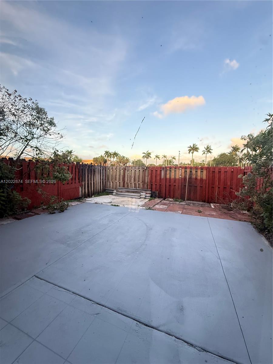 A fenced backyard features a gray concrete patio and a small set of steps — 18615 NW 84th Pl # 1, Hialeah FL 33015, HIALEAH, FL