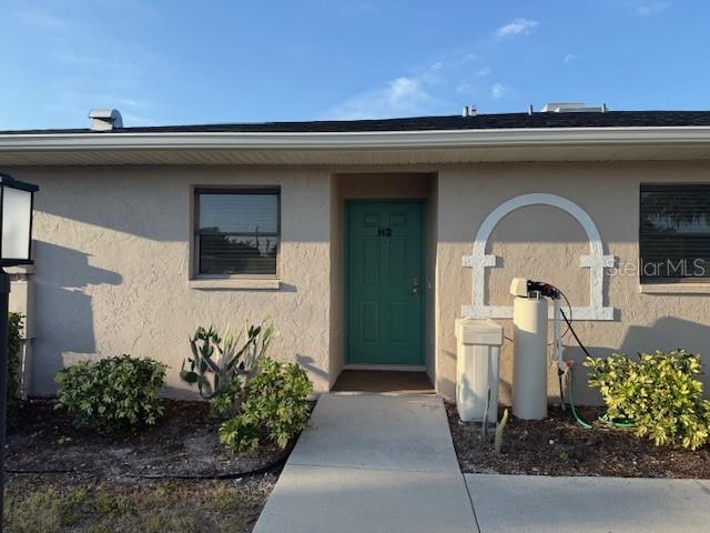 A teal front door labeled H2 is centered on the exterior of a tan building — 24540 HARBORVIEW ROAD UNIT H2, PUNTA GORDA, FL