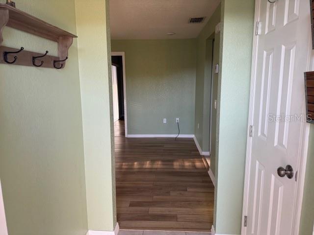 A hallway with light green walls, wood-look flooring, and a wall-mounted coat rack — 24540 HARBORVIEW ROAD UNIT H2, PUNTA GORDA, FL