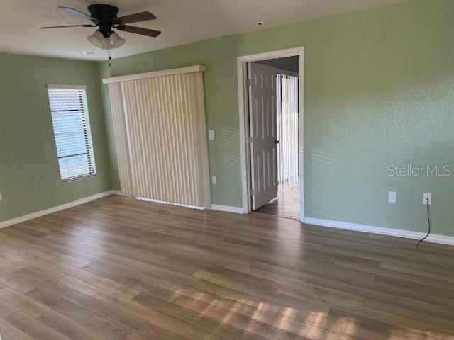 A room with light green walls, wood-look flooring, a ceiling fan, and a sliding glass door — 24540 HARBORVIEW ROAD UNIT H2, PUNTA GORDA, FL
