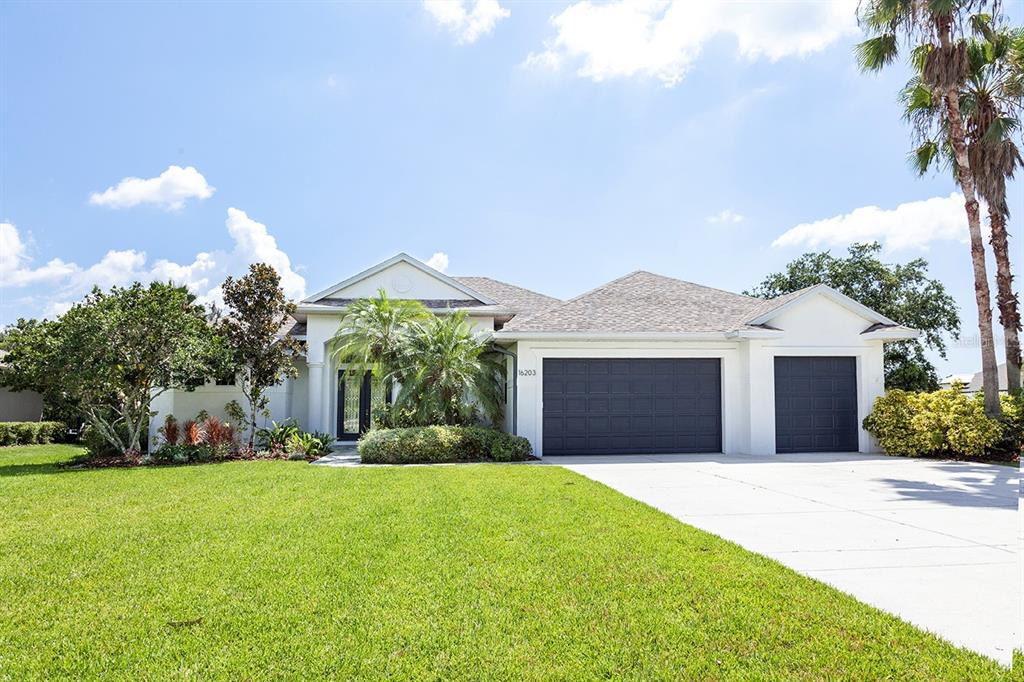 A single-story house with a white exterior, dark garage doors, and a manicured front lawn — 16203 33RD COURT E, PARRISH, FL
