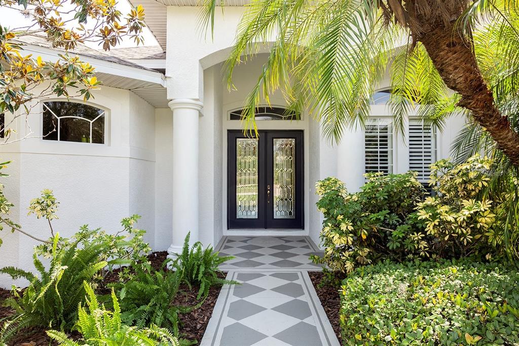 A white house exterior features a double front door with glass panels and diamond-patterned flooring — 16203 33RD COURT E, PARRISH, FL