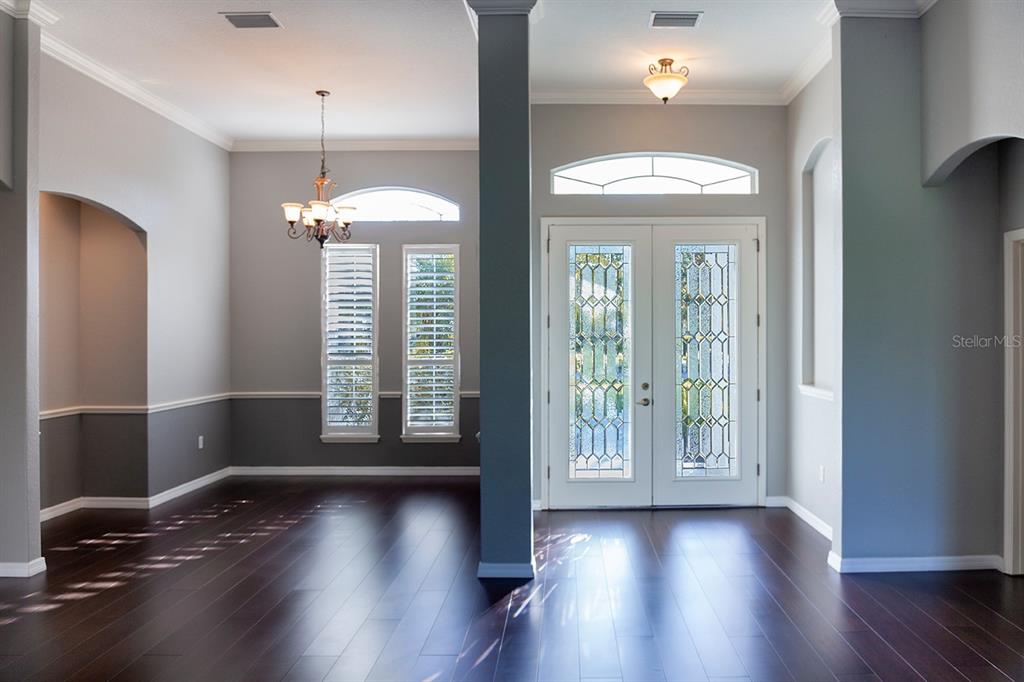A foyer and dining area feature dark hardwood floors, gray walls, and double glass doors — 16203 33RD COURT E, PARRISH, FL