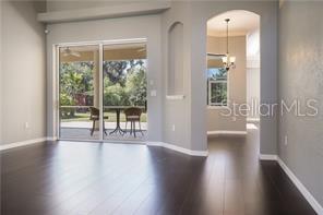 A living area with dark hardwood floors leads to a sliding glass door and patio — 16203 33RD COURT E, PARRISH, FL