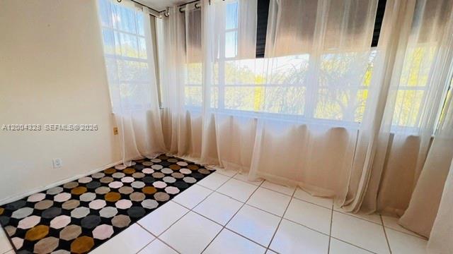 A sunroom with white tile floors, a geometric rug, and sheer curtains over large windows — 6500 Cypress Rd # 402, Plantation FL 33317, PLANTATION, FL