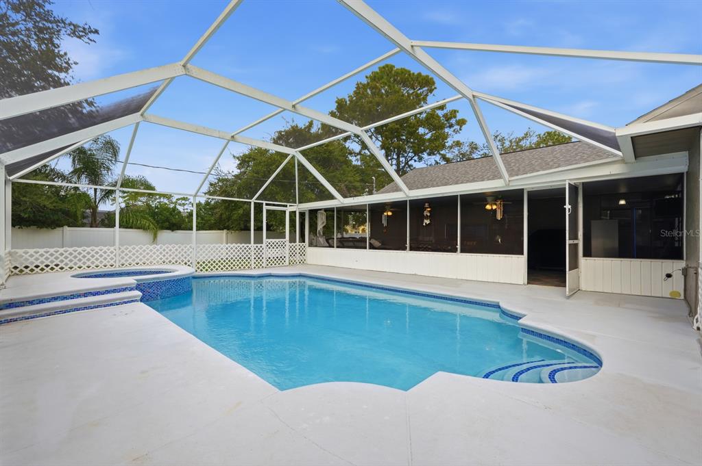 A screened-in swimming pool and hot tub sit on a concrete patio behind a house — 3153 BYINGTON TERRACE, DELTONA, FL