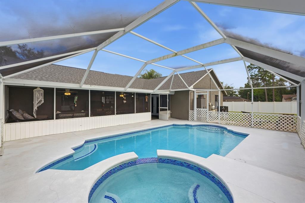 A screened-in patio features a swimming pool and a circular hot tub with blue tiles — 3153 BYINGTON TERRACE, DELTONA, FL