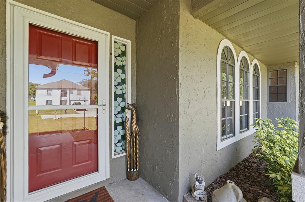 A front porch features a red storm door, a floral sidelight, and three arched windows — 3153 BYINGTON TERRACE, DELTONA, FL