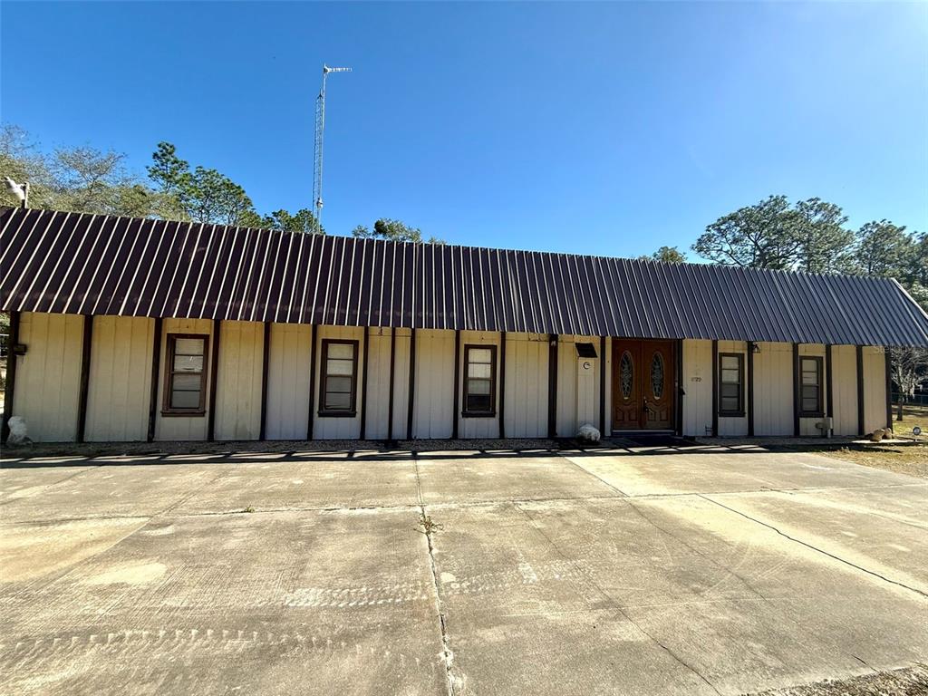 A single-story building with a metal roof and a large concrete driveway in front — 1180 SW 158TH AVENUE, OCALA, FL