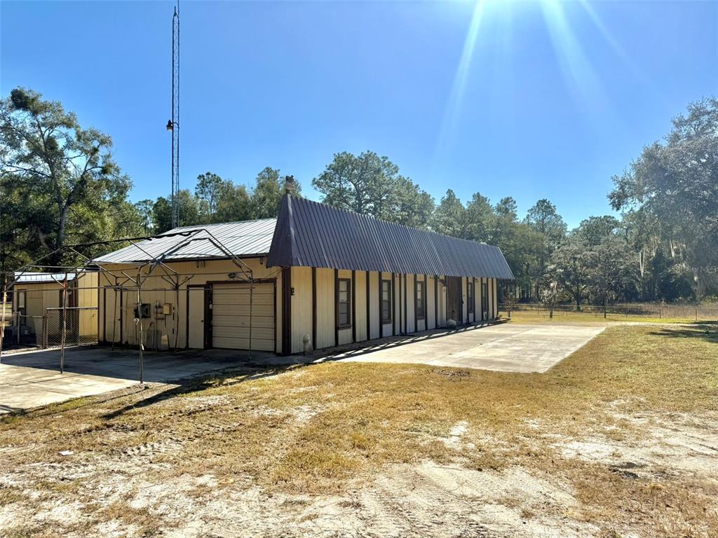 A single-story building with a metal roof and light-colored siding stands on a grassy lot — 1180 SW 158TH AVENUE, OCALA, FL