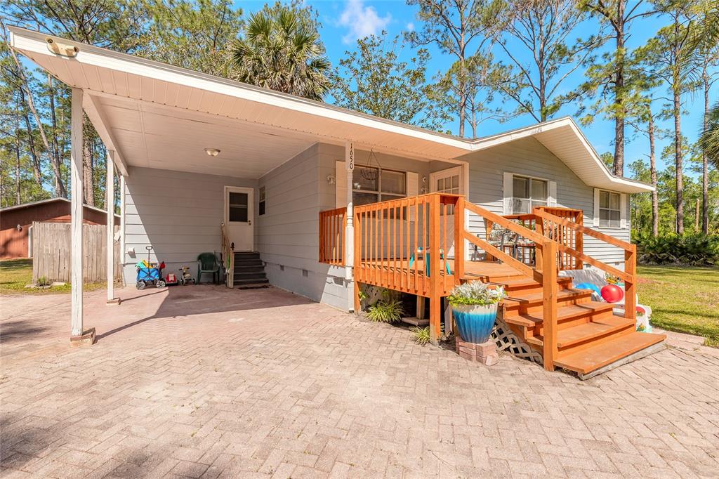 A single-story house with a carport, a wooden deck, and a paved driveway — 1650 11TH AVENUE, DELAND, FL