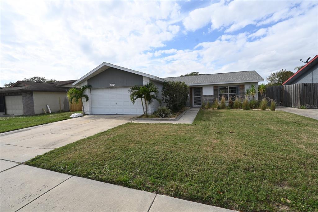 A single-story house with a white garage, gray siding, and a front lawn — 6524 MAUNA LOA BOULEVARD, SARASOTA, FL