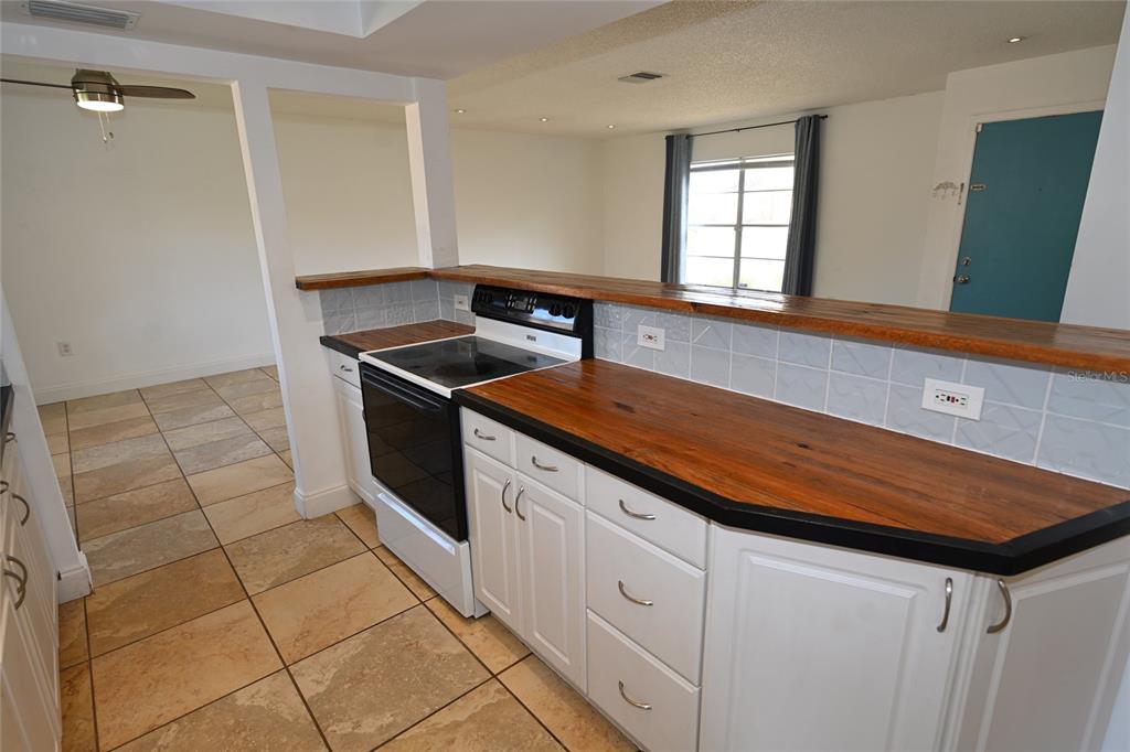 A kitchen features white cabinets, a wooden countertop, and a black stove — 6524 MAUNA LOA BOULEVARD, SARASOTA, FL