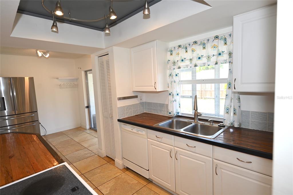 A kitchen features white cabinets, dark wood countertops, a double sink, and tile flooring — 6524 MAUNA LOA BOULEVARD, SARASOTA, FL