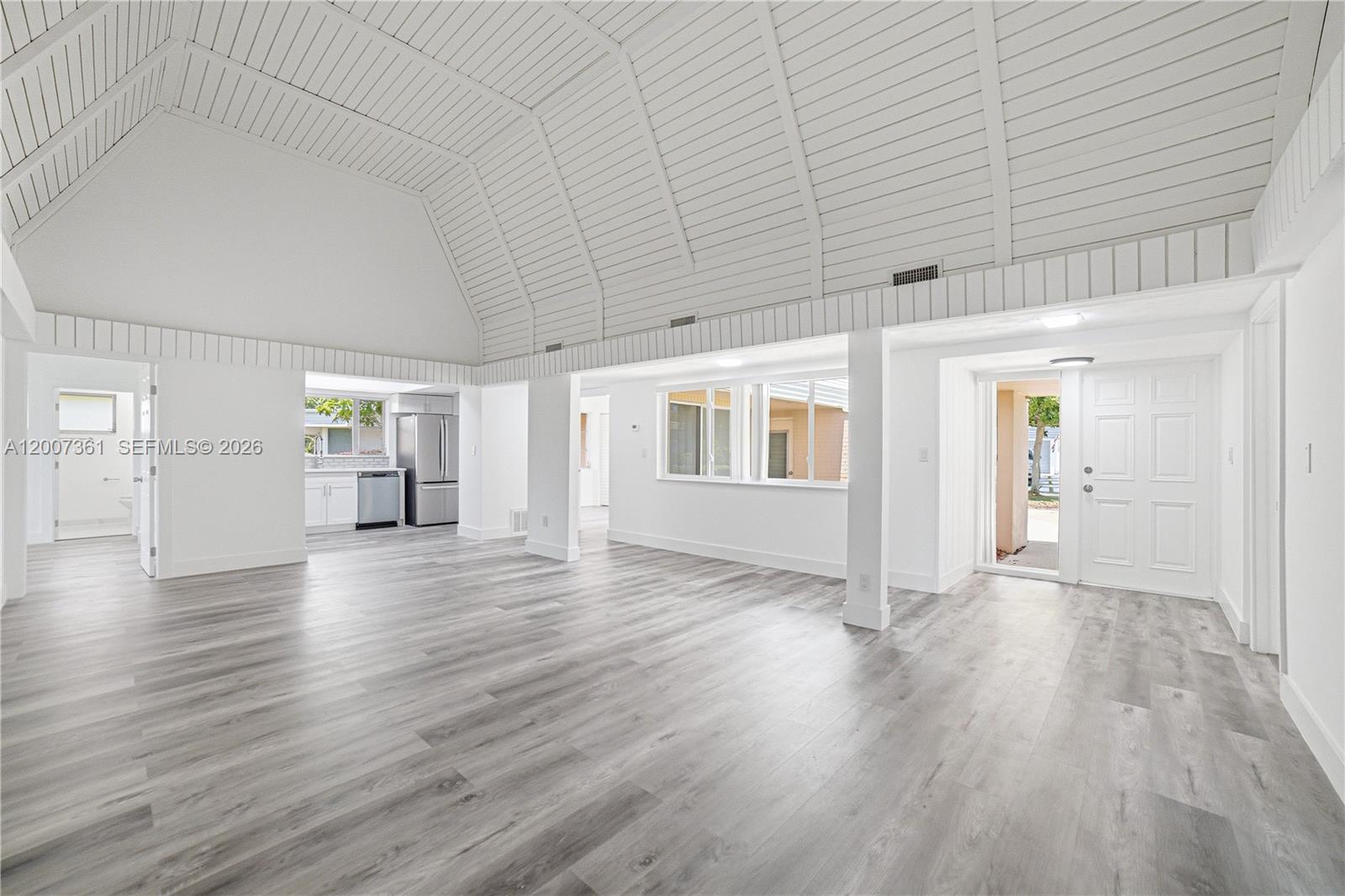An open-concept living area features a vaulted wood-paneled ceiling, white walls, and gray flooring — 5201 Yellow Pine Ln, Tamarac FL 33319, TAMARAC, FL