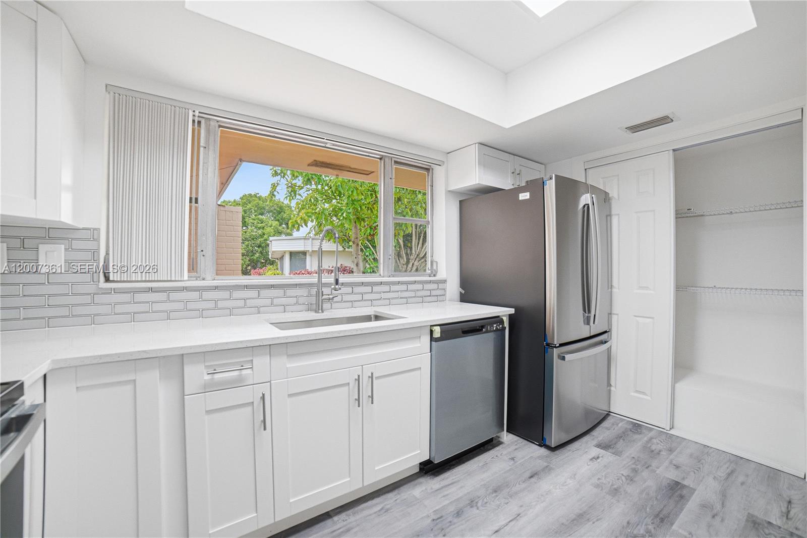 A kitchen features white cabinets, stainless steel appliances, a subway tile backsplash, and gray flooring — 5201 Yellow Pine Ln, Tamarac FL 33319, TAMARAC, FL