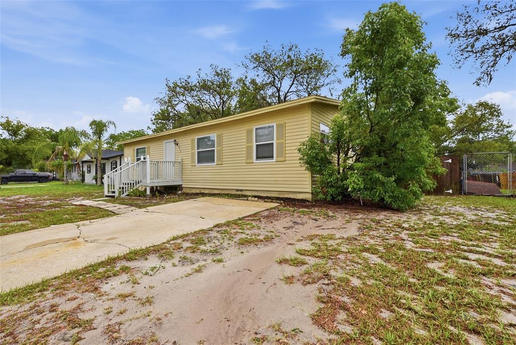 A yellow single-story house with a concrete driveway and a small wooden porch — 956 OSCEOLA TRAIL, CASSELBERRY, FL