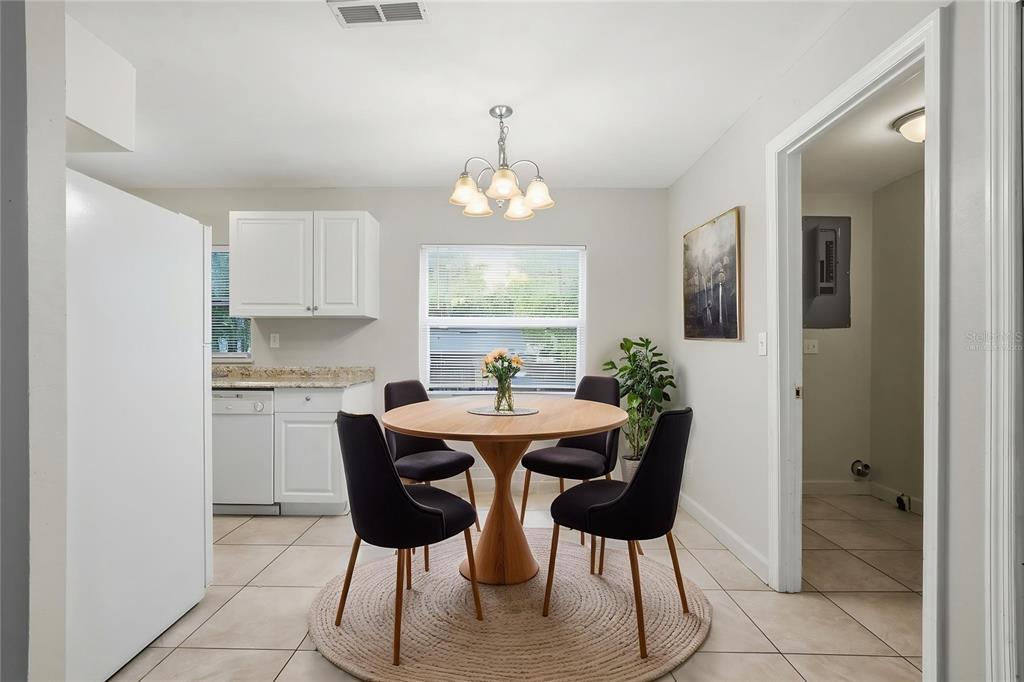 A dining area with a round wooden table, four black chairs, and a light fixture — 956 OSCEOLA TRAIL, CASSELBERRY, FL
