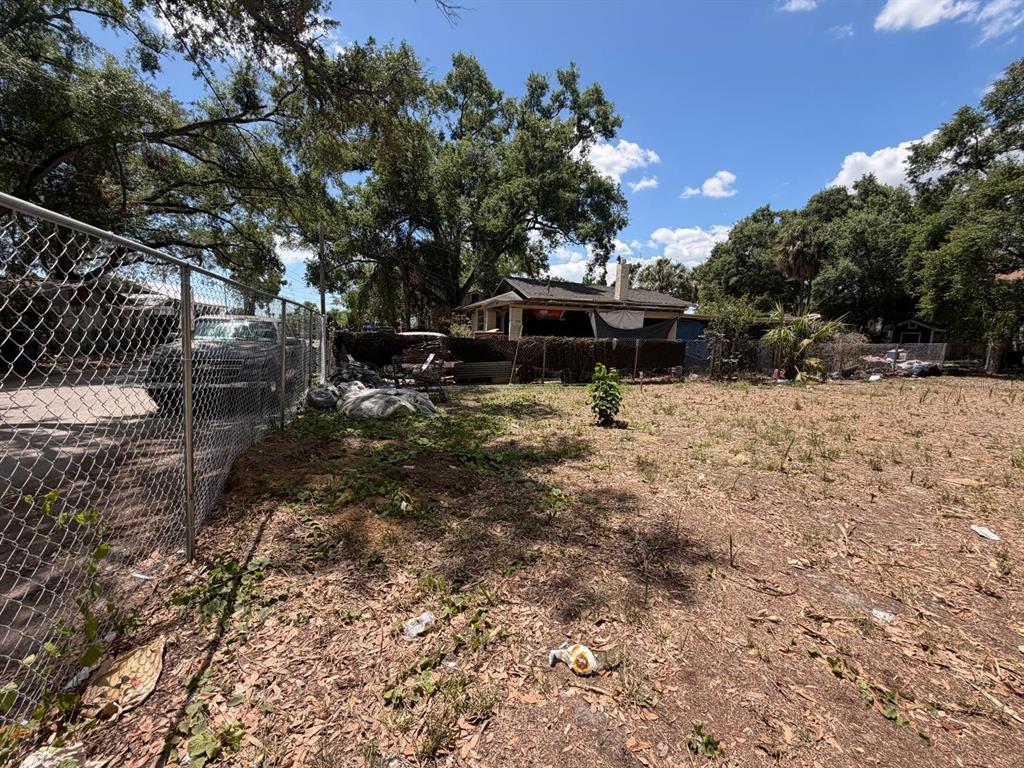 A vacant, grassy lot sits next to a chain-link fence and a neighboring house — 4904 E 8TH AVENUE, TAMPA, FL